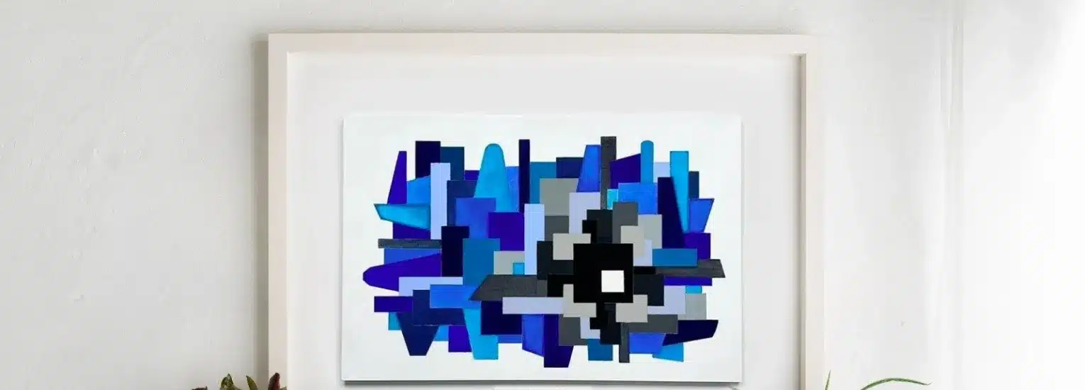 A framed abstract painting with overlapping blue, navy, and grey geometric shapes hangs on a white wall above a shelf with potted plants.