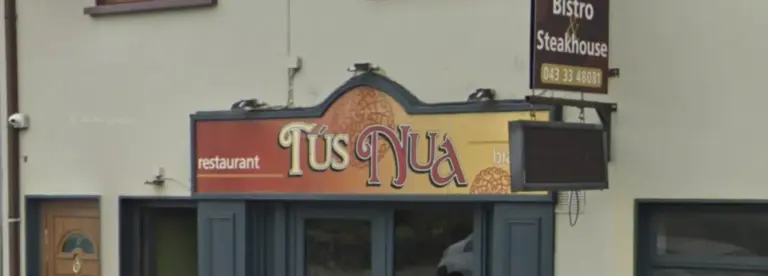 A restaurant shopfront with a sign reading "Tús Nua" in decorative font, along with "restaurant" and "bistro" on either side. Above, there is a sign for "Bistro & Steakhouse.