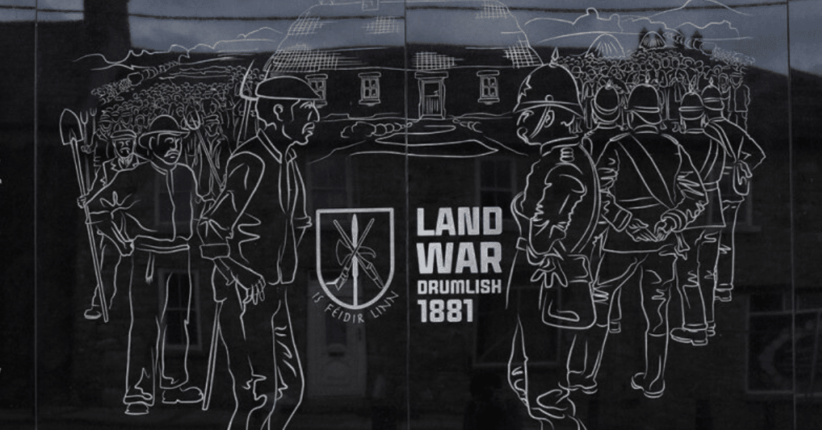 Line drawing on a plaque depicts men with tools facing armed officers in front of a building. Text reads “LAND WAR DRUMLISH 1881” with an emblem and Irish phrase, referencing an historical event.
