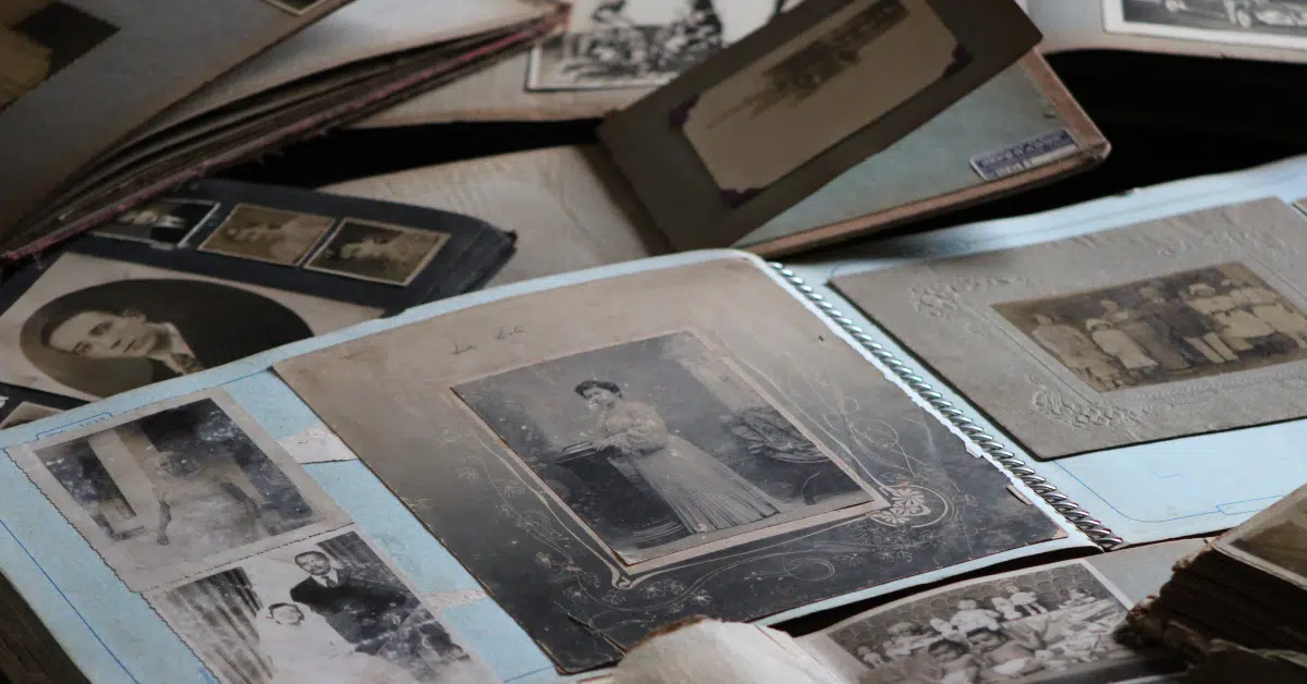 Several vintage photo albums are open, displaying black-and-white and sepia photographs of people, including portraits and group photos, on a wooden surface.